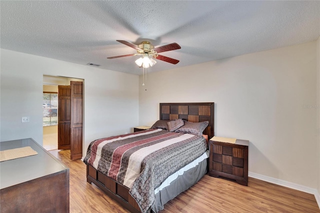 bedroom featuring ceiling fan, light hardwood / wood-style floors, and a textured ceiling