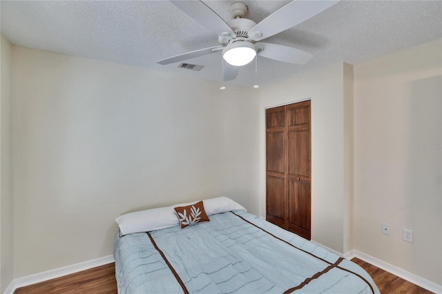 bedroom with hardwood / wood-style flooring, ceiling fan, and a textured ceiling