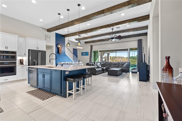 kitchen with pendant lighting, sink, black appliances, an island with sink, and white cabinets