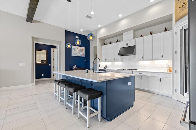 kitchen with pendant lighting, sink, a breakfast bar area, white cabinetry, and a kitchen island with sink