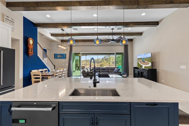 kitchen featuring high quality fridge, pendant lighting, blue cabinets, an island with sink, and sink