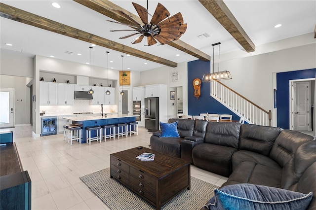 living room featuring wine cooler, sink, beam ceiling, and an inviting chandelier