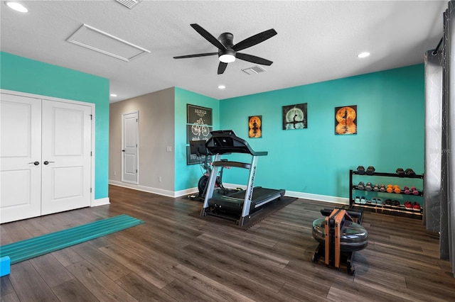 workout room with ceiling fan, dark wood-type flooring, and a textured ceiling