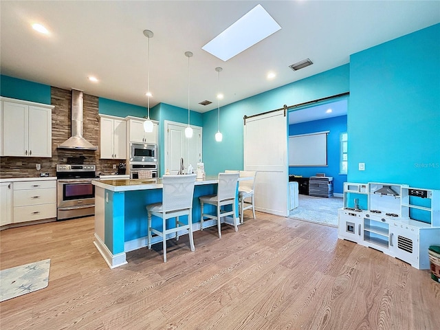 13653 Heritage Way, Sarasota, FL 34240 - kitchen featuring appliances with stainless steel finishes, a breakfast bar, pendant lighting, a barn door, and wall chimney exhaust hood