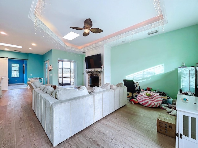 13653 Heritage Way, Sarasota, FL 34240 - living room with a raised ceiling, a barn door, and light hardwood / wood-style flooring