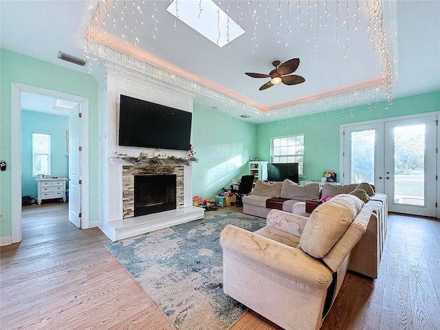 13653 Heritage Way, Sarasota, FL 34240 - living room featuring ceiling fan, wood-type flooring, french doors, a stone fireplace, and a raised ceiling