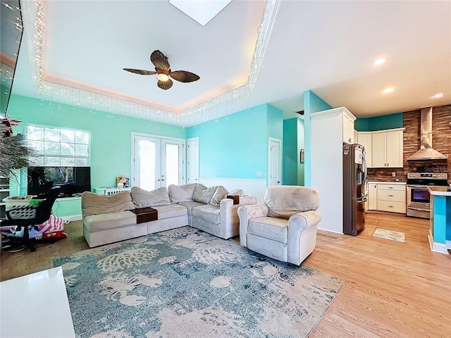 13653 Heritage Way, Sarasota, FL 34240 - living room with a tray ceiling, light hardwood / wood-style flooring, french doors, and ceiling fan