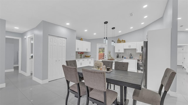 dining space featuring lofted ceiling, sink, and light tile patterned floors