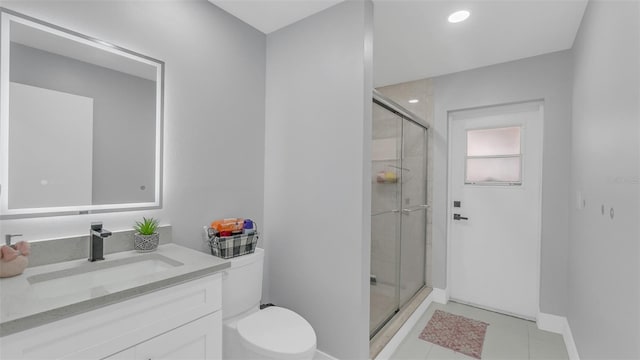 bathroom with tile patterned flooring, vanity, toilet, and walk in shower