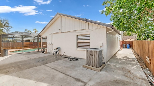 rear view of property with a patio, a lanai, an empty pool, and cooling unit