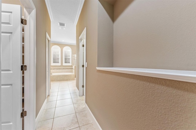 corridor with ornamental molding, a textured ceiling, and light tile patterned floors