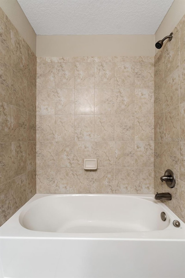 bathroom with tiled shower / bath and a textured ceiling