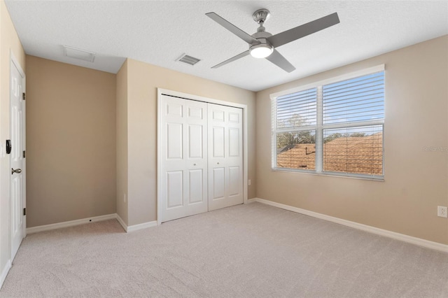 unfurnished bedroom featuring light carpet, ceiling fan, a closet, and a textured ceiling