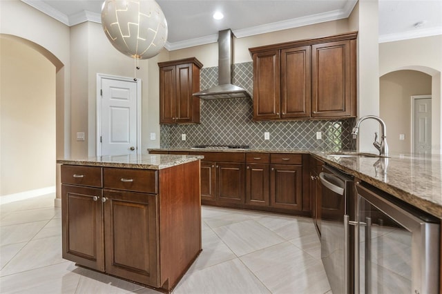 kitchen with wine cooler, sink, ornamental molding, light stone countertops, and wall chimney range hood