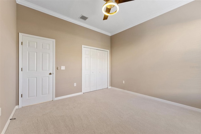 unfurnished bedroom with crown molding, carpet flooring, ceiling fan, and a closet