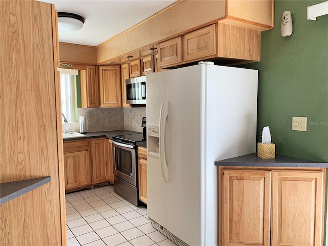 kitchen featuring sink, decorative backsplash, light tile patterned floors, and appliances with stainless steel finishes