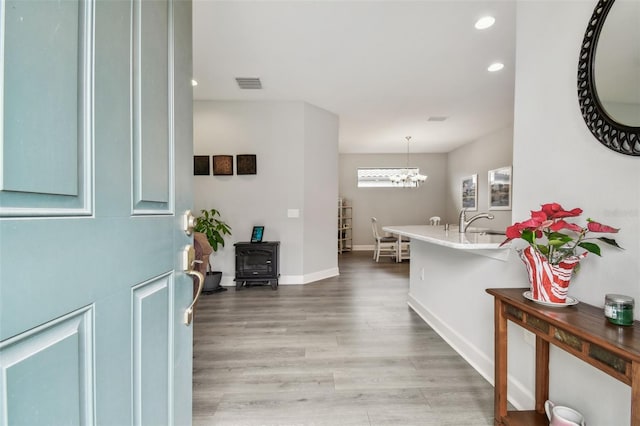 entrance foyer with visible vents, baseboards, recessed lighting, light wood-style flooring, and a wood stove