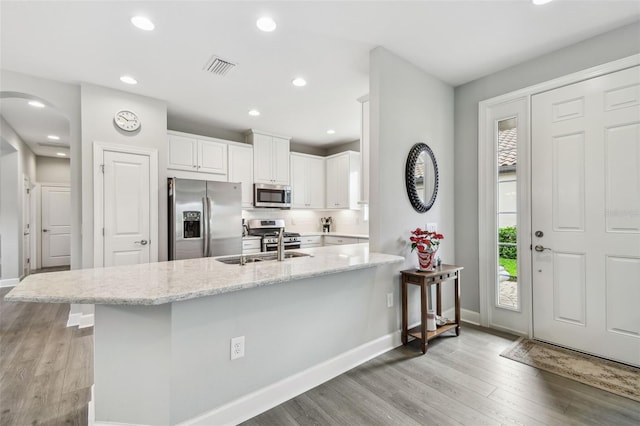 kitchen featuring white cabinetry, light wood-style flooring, a wealth of natural light, and stainless steel appliances