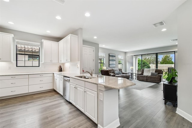 kitchen with white cabinetry, decorative backsplash, light stone counters, kitchen peninsula, and light wood-type flooring