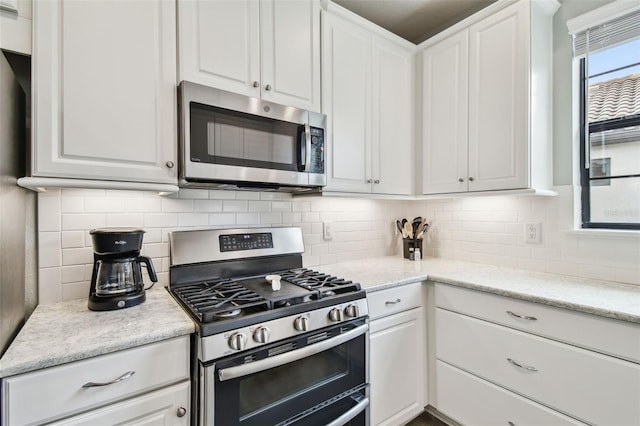 kitchen featuring stainless steel appliances, white cabinetry, and backsplash