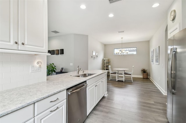 kitchen featuring stainless steel appliances, white cabinetry, sink, and pendant lighting