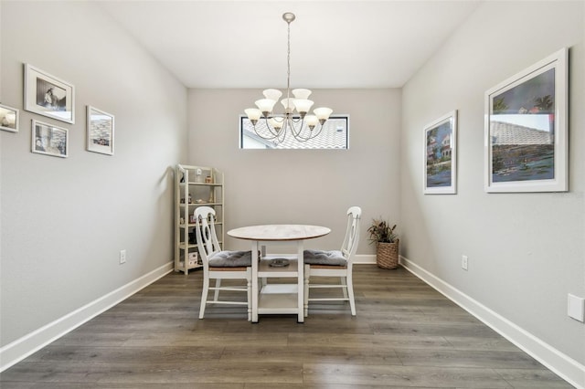 dining space featuring baseboards, a notable chandelier, and wood finished floors