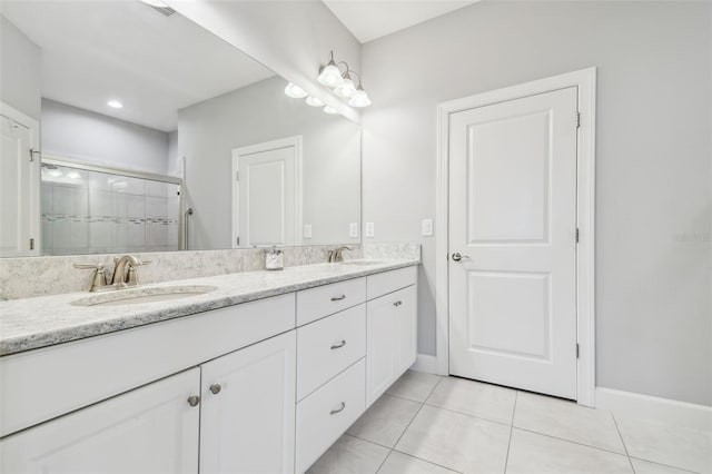 full bathroom featuring tile patterned flooring, double vanity, tiled shower, and a sink