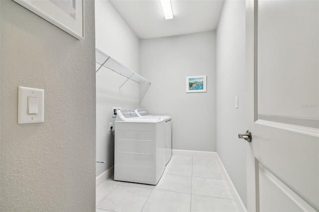 washroom with baseboards, light tile patterned flooring, laundry area, and washer and clothes dryer