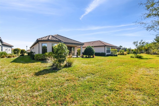 exterior space with a front lawn, a tiled roof, and stucco siding