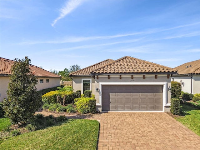 mediterranean / spanish house with a tiled roof, decorative driveway, an attached garage, and stucco siding