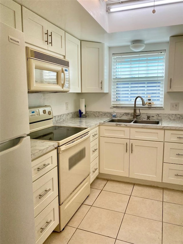 kitchen with light tile patterned flooring, sink, white cabinets, and white appliances