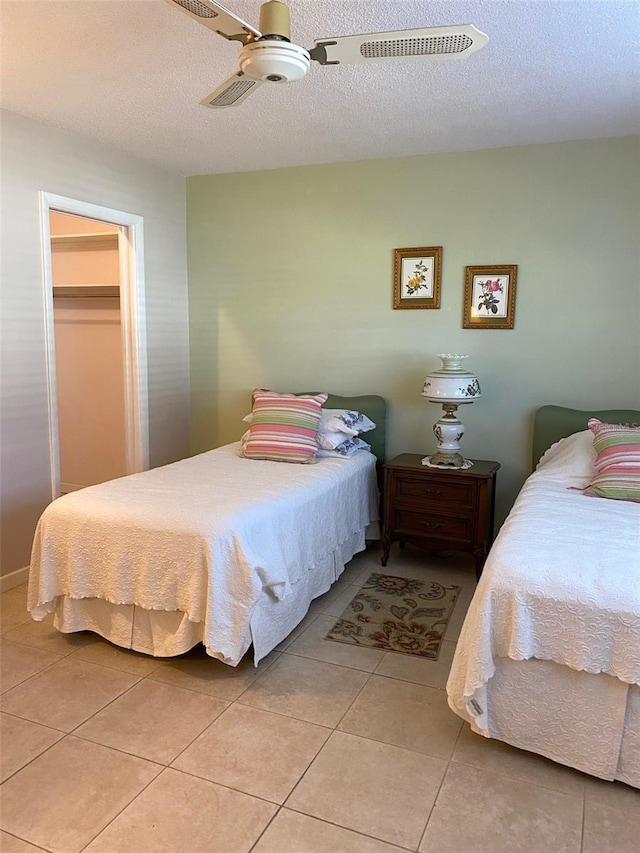 bedroom featuring a spacious closet, light tile patterned floors, ceiling fan, a textured ceiling, and a closet