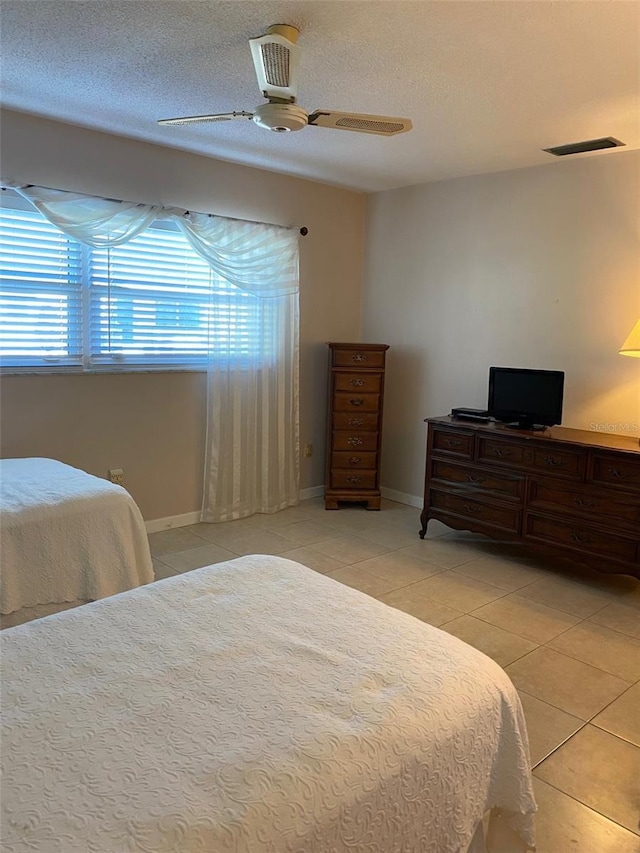 tiled bedroom featuring a textured ceiling and ceiling fan