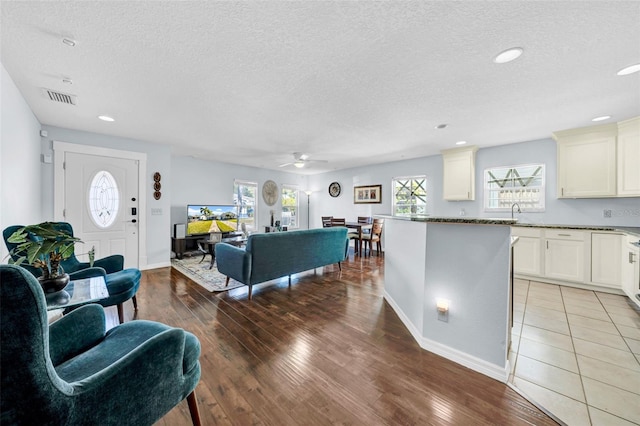 living room featuring ceiling fan, light hardwood / wood-style floors, and a textured ceiling