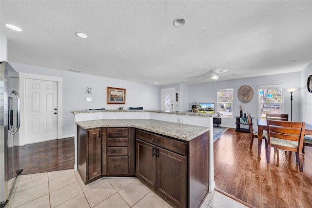 kitchen featuring light stone counters, light tile patterned floors, and stainless steel refrigerator with ice dispenser