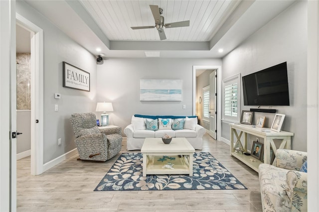 living room with ceiling fan, wooden ceiling, light wood-type flooring, and a tray ceiling