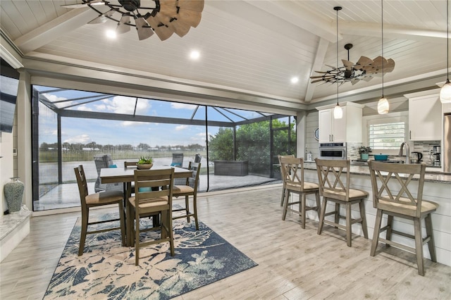 dining space with a wealth of natural light, lofted ceiling with beams, ceiling fan, and light wood-type flooring