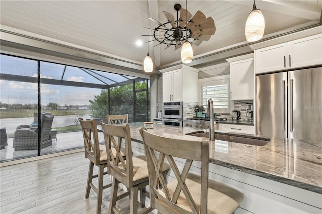 kitchen featuring hanging light fixtures, appliances with stainless steel finishes, white cabinets, and dark stone counters