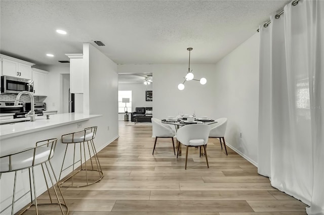 dining room with a textured ceiling, ceiling fan, and light wood-type flooring