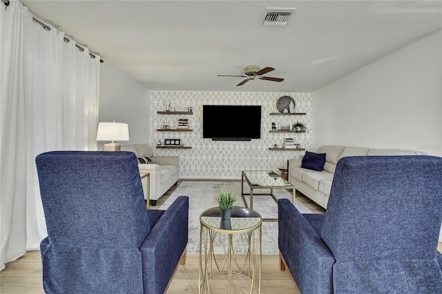 living room with ceiling fan and a textured ceiling