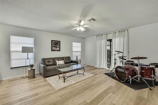 living room featuring a textured ceiling, ceiling fan, and light hardwood / wood-style flooring