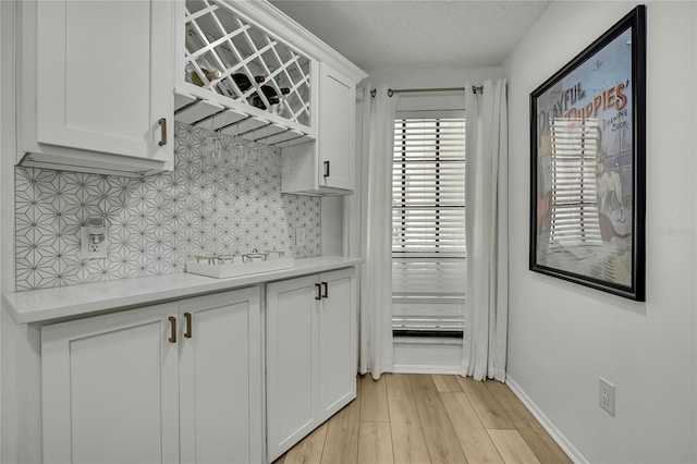 kitchen with tasteful backsplash, white cabinets, and light wood-type flooring