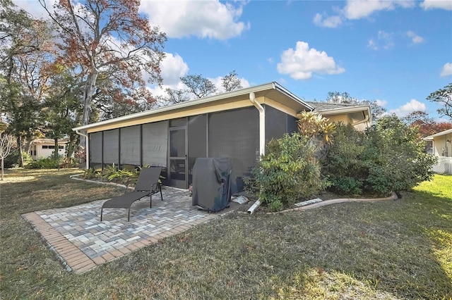 rear view of house with a yard, a patio, and a sunroom