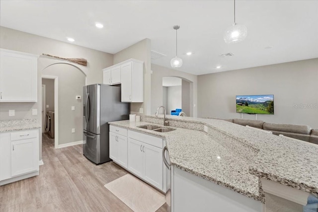 kitchen featuring white cabinetry, sink, pendant lighting, and light wood-type flooring