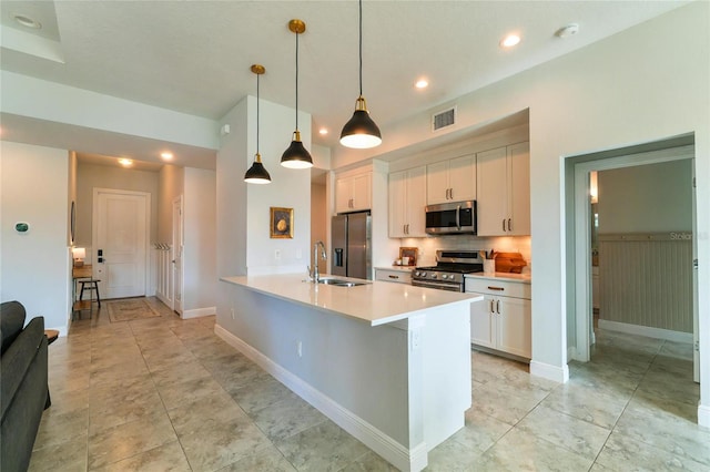 kitchen with appliances with stainless steel finishes, pendant lighting, tasteful backsplash, white cabinetry, and sink