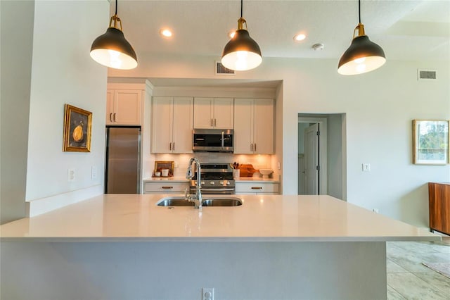 kitchen with sink, decorative light fixtures, white cabinets, and appliances with stainless steel finishes