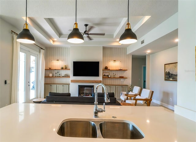 kitchen featuring sink, decorative light fixtures, a raised ceiling, and ceiling fan