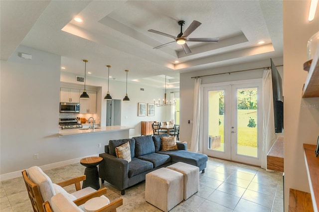 living room with sink, light tile patterned floors, a raised ceiling, and french doors