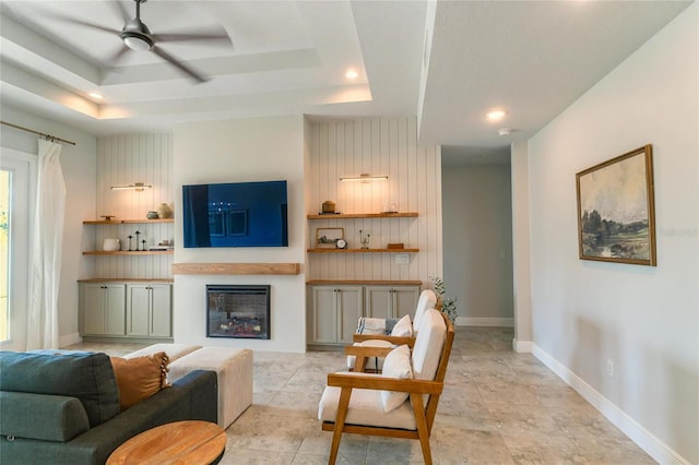 living room featuring ceiling fan and a tray ceiling