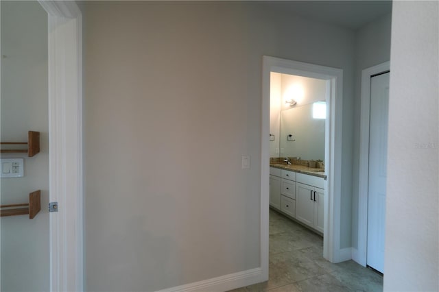 corridor featuring sink and light tile patterned floors